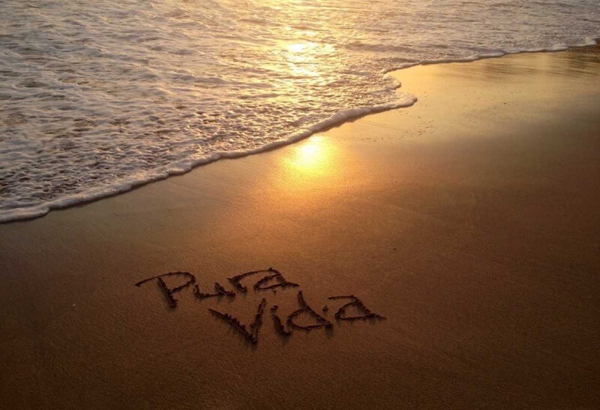 Pura Vida written in the sand on a beach